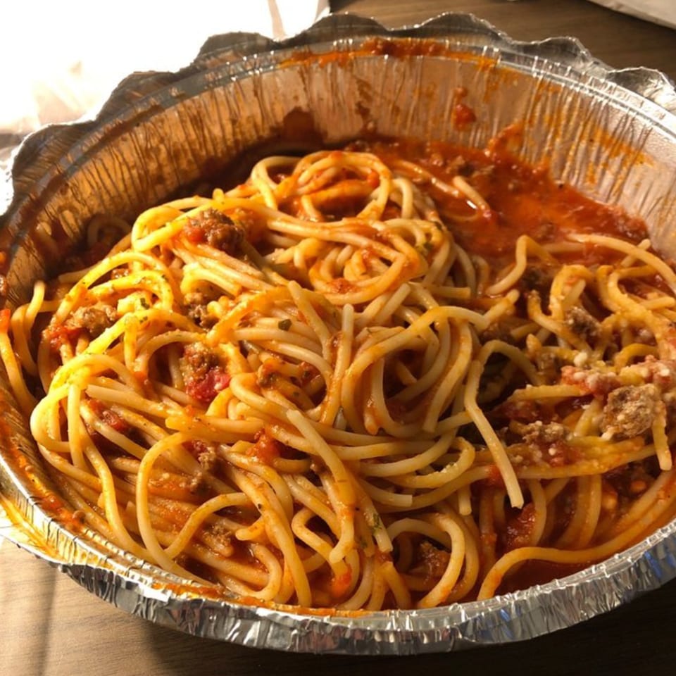 Spaghetti with meat sauce and parmesan cheese in a foil take-out container from Jordana's Pizzeria.